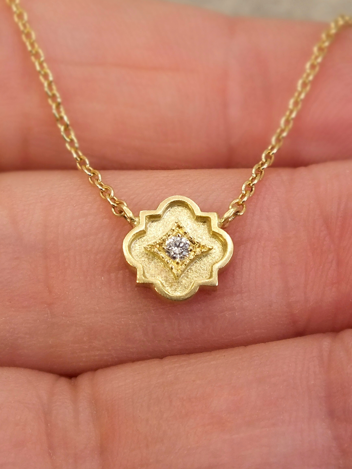 delicate 18k gold station necklace featuring a tiny quatrefoil pendant set with a sparkling diamond in a millgrain-bordered frame. Inspired by Gothic architecture and sacred geometry, this necklace is a modern talisman of light, protection, and inner radiance.